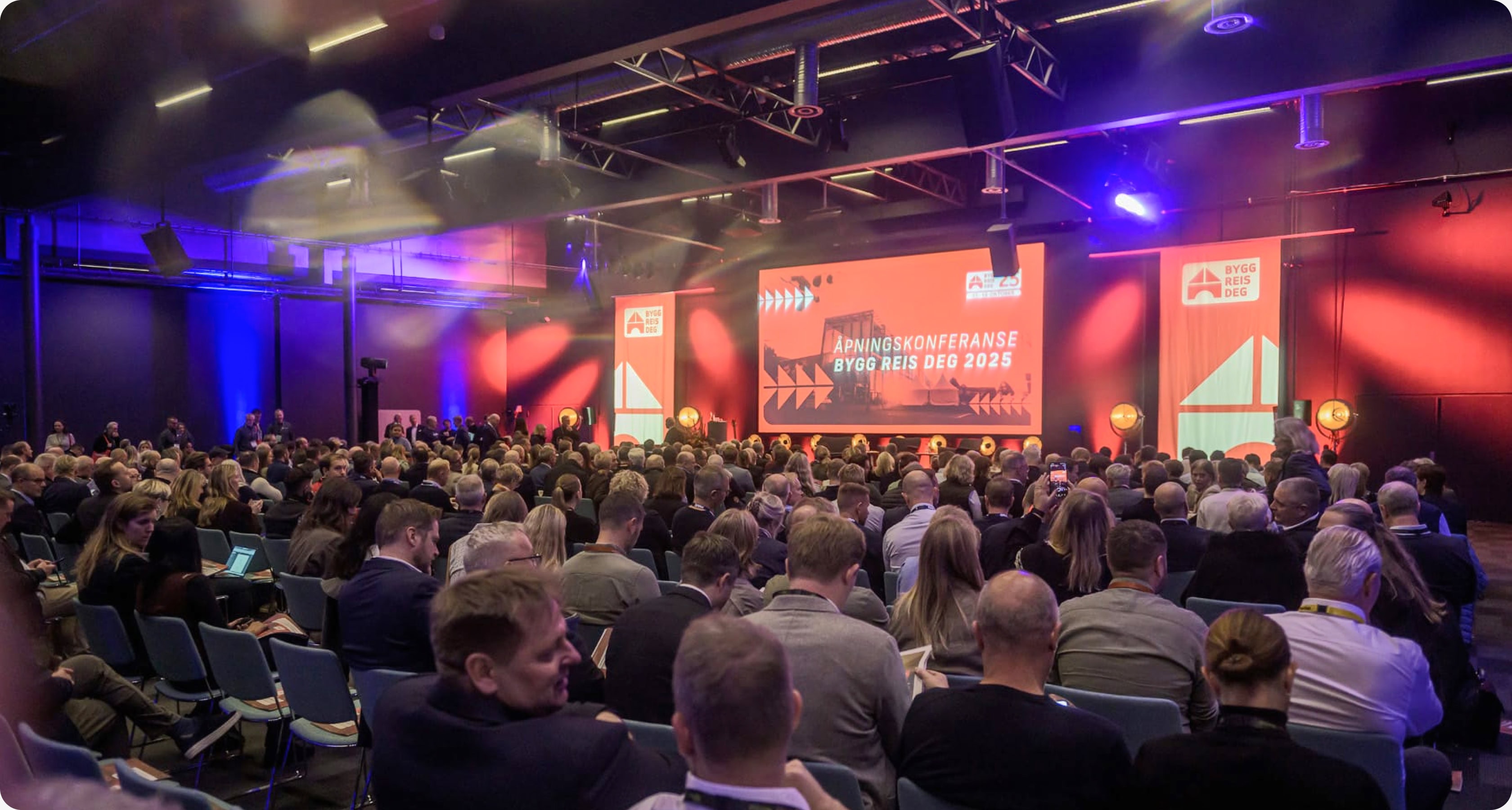 Fullsatt konferansesal under åpningskonferansen Bygg Reis Deg 2025, med scene, storskjerm og tydelig profilering.