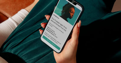 En person holder en mobiltelefon med en digital konsertbillett på skjermen, som viser konsertsted, tid og billettinformasjon.